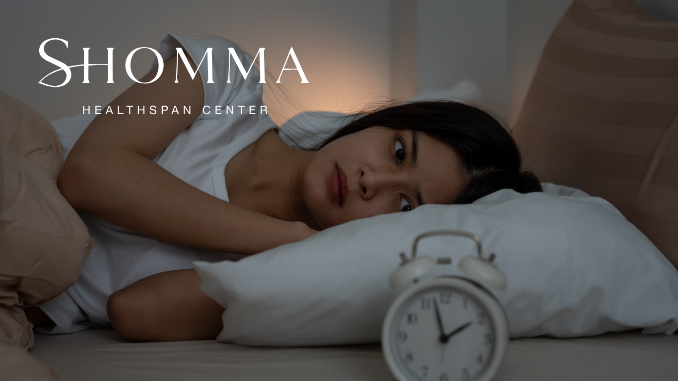 Woman awake in bed next to an alarm clock, symbolising morning fatigue despite eight hours of sleep.